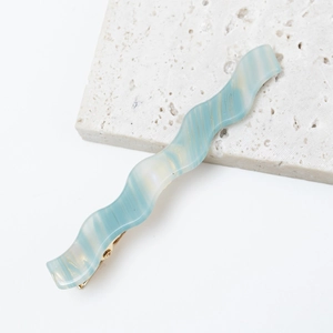 Close-up of wavy blue and cream acetate hair clip with gold metal duckbill clamp