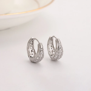 Boucles d'oreilles créoles évidées en argent avec pavé de zircons sur fond épuré