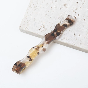 Detailed close-up of a tortoiseshell wave acetate hair clip on a textured stone display
