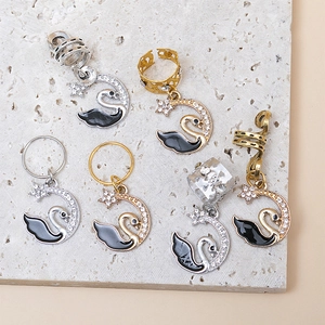 Macro detail of swan-shaped hair charms with crystals and moon motifs for braids