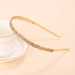 Elegant twisted gold alloy headband with zircon rhinestones on a ceramic cup background