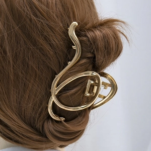 Close-up of golden irregular metal hair claw clip styled on long brown hair in detail