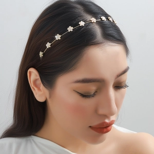 Elegante diadema de metal dorado con flores blancas y perlas en una modelo