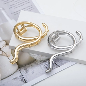 Irregular minimalist metal hair claw clips in gold and silver on white marble stand