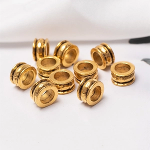 Macro shot of vintage gold cylinder beads with grooved texture for African dreadlock braids