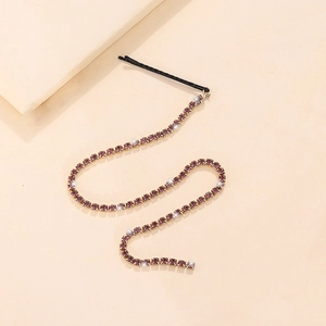 Close-up of black hair clip with long purple rhinestone fringe and snake chain tassels