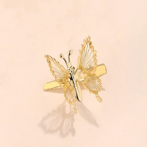 Vista detallada de la pinza de pelo mariposa dorada con textura de filigrana metálica
