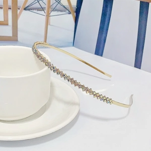 Détail d'un serre-tête fin en métal doré avec des strass AB colorés étincelants sur une tasse