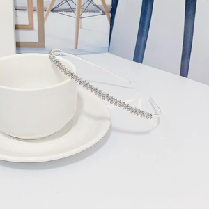 Serre-tête fin en métal argenté avec strass brillants sur une tasse à café blanche