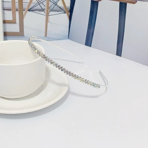 Serre-tête élégant en métal argenté avec strass irisés posé sur une tasse blanche