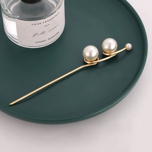 Elegant gold hair pin with three cream pearls on a minimalist spiral design