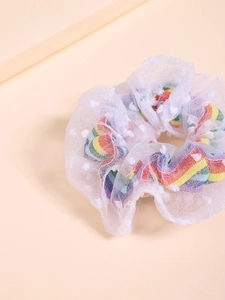 Detailed macro view of white mesh scrunchie with rainbow heart prints and fuzzy pom-poms