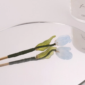 Detailed view of light blue tulip hair pin with green silk wrap on a mirror