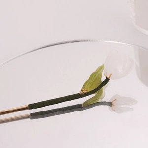 Detailed view of handmade tulip hairpin with green thread wrapping and gold metal stem