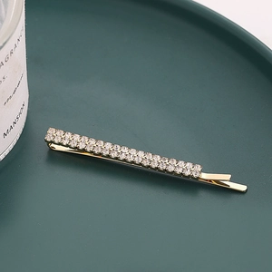 Barrette dorée élégante avec double rangée de strass étincelants sur un plateau vert foncé