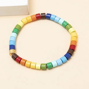 Colorful cylindrical beaded bracelet with gold accent bead on minimalist background