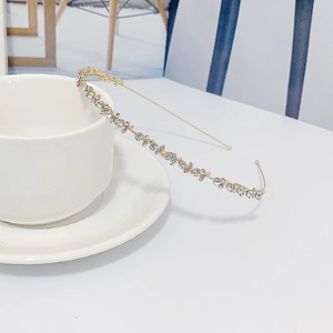 Vue détaillée d'un serre-tête en strass dorés posé sur une tasse en céramique