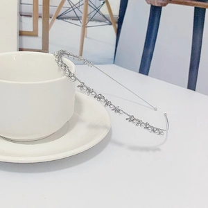 Serre-tête élégant en métal argenté avec perles blanches et cristaux sur une tasse