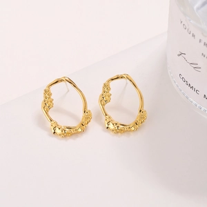Minimalist irregular gold-plated lava texture oval earrings on a white display stand