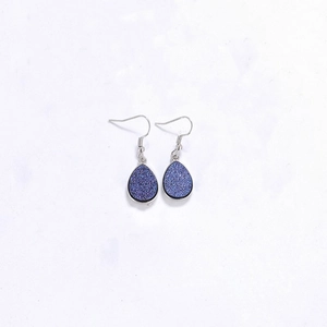 Gros plan de boucles d'oreilles en résine druzy bleu foncé avec crochets argentés