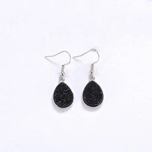 Détail de boucles d'oreilles argentées avec pierre druzy noire en forme de goutte
