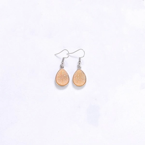 Détail de boucles d'oreilles druzy orange en goutte avec texture brillante et crochets