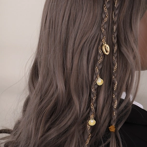 Elegant gold hair chain with shell charms and pearls woven into purple braided hair