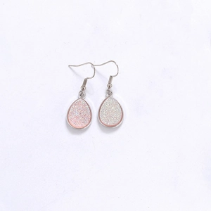 Vue détaillée de boucles d'oreilles en résine cristal en goutte sur fond blanc pur