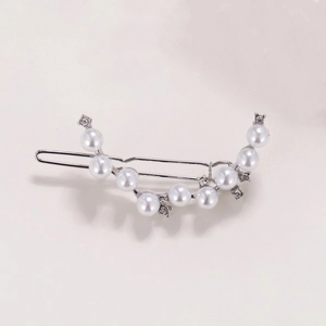 Close-up of silver hair clip with elegant pearls and sparkling rhinestones on grey background