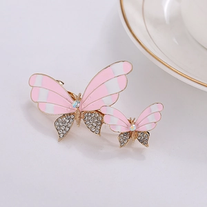 Detailed macro of golden metal butterfly hair clips with pink enamel and sparkling rhinestones