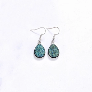 Détail de boucles d'oreilles argentées goutte avec paillettes druzy bleu sarcelle