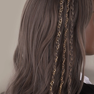 Detail of long gold chain hair accessories braided into long wavy brown hair