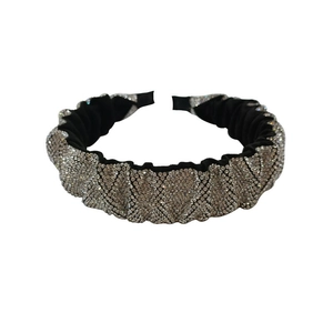 Détail d'un serre-tête en tissu plissé noir orné de strass argentés brillants pour femme