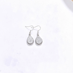 Vue détaillée des boucles d'oreilles argentées en goutte avec finition scintillante