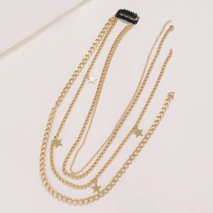Layered gold star pendant hair chain with Cuban link and star charms on beige background