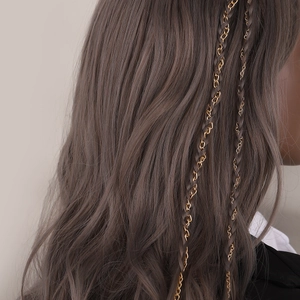 Detail of golden metal chain woven into long wavy hair for elegant ponytail styling