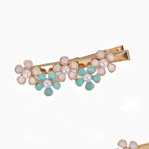 Dettaglio del fermaglio floreale con petali in smalto rosa e verde e perle finte