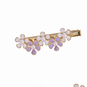 Dettaglio del fermaglio dorato con cinque fiori in smalto e perle artificiali al centro