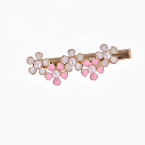 Dettaglio del fermaglio fiori rosa e bianchi con perle sintetiche su base dorata