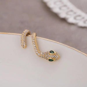 Manchette d'oreille serpent dorée avec pavé de zircons et yeux en pierres vertes sur porcelaine