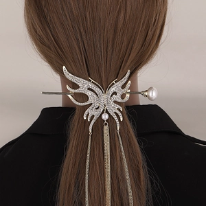 Detailed view of a crystal butterfly hair pin with pearls and golden hanging tassels