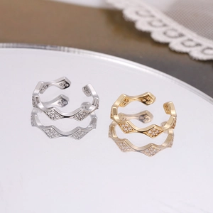 Detail of adjustable wave-shaped rings in gold and silver finish with pavé set crystals