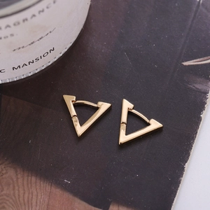 Boucles d'oreilles créoles triangulaires dorées minimalistes sur fond sombre texturé