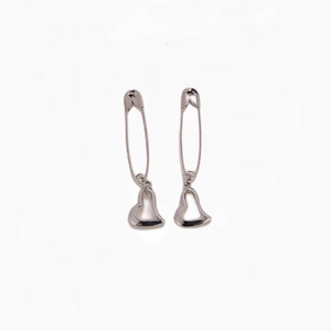 Macro shot of silver gothic safety pin earrings featuring minimalist hollow heart charms