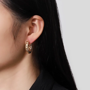 Close-up of gold-plated hollow hoop earrings featuring intricate lattice texture on model