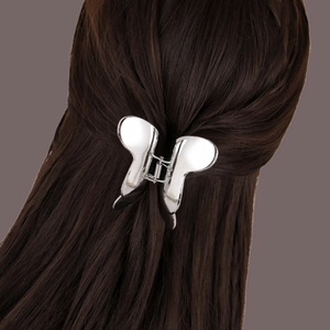 Pince à cheveux papillon en métal argenté brillant sur une coiffure mi-haute