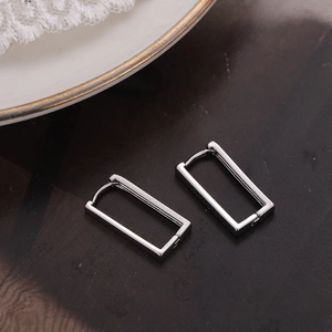Minimalist silver rectangular hoop earrings displayed on a dark textured background