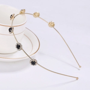 Close-up of golden sunflower headband with black gemstone and sparkling crystals