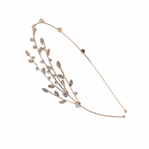 Détail d'un serre-tête doré avec feuilles et strass scintillants sur un fond blanc pur