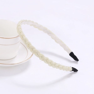 Close-up of cream beaded braided headband resting on a white coffee cup edge
